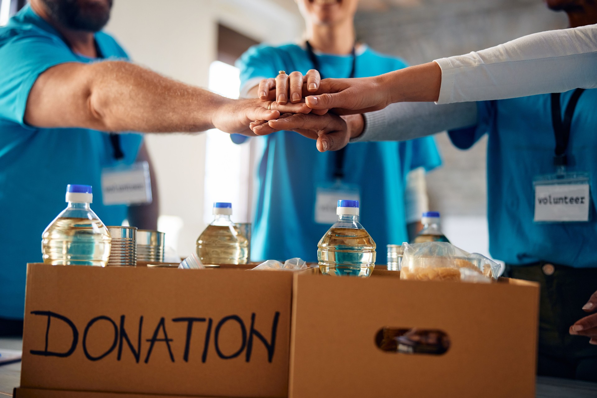 Close up of volunteer team gathering hands in unity at food bank.